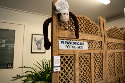 Please ring for service.  A monkey hanging on a wall pointing at the sign to ring bell.